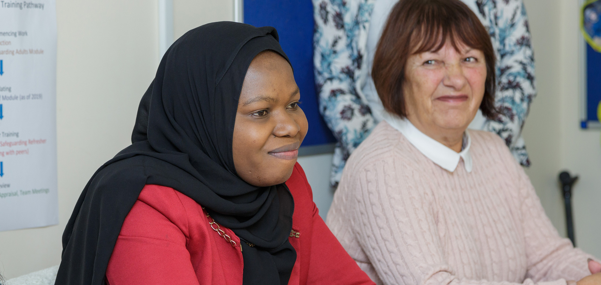 Two ladies sat at a board table, smiling